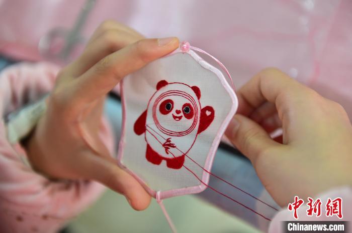 圖為一名小學(xué)生正在繡制2022年北京冬奧會(huì)吉祥物“冰墩墩”形象?！∮髟屏?攝