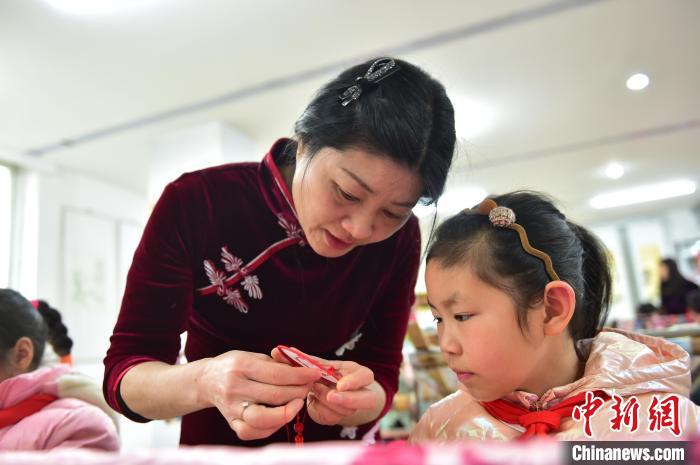 江西省級(jí)非遺豫章繡傳承人手把手指導(dǎo)小學(xué)生繡制2022年北京冬奧會(huì)吉祥物“冰墩墩”形象。　喻云亮 攝