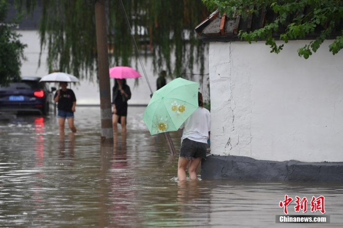 7月31日，市民行走在雨中的北京房山區(qū)瓦窯頭村。北京市氣象臺(tái)當(dāng)日10時(shí)發(fā)布分區(qū)域暴雨紅色預(yù)警信號(hào)。北京市水文總站發(fā)布洪水紅色預(yù)警，預(yù)計(jì)當(dāng)日12時(shí)至14時(shí)，房山區(qū)大石河流域?qū)⒊霈F(xiàn)紅色預(yù)警標(biāo)準(zhǔn)洪水。<a target='_blank' href='/'><p  align=