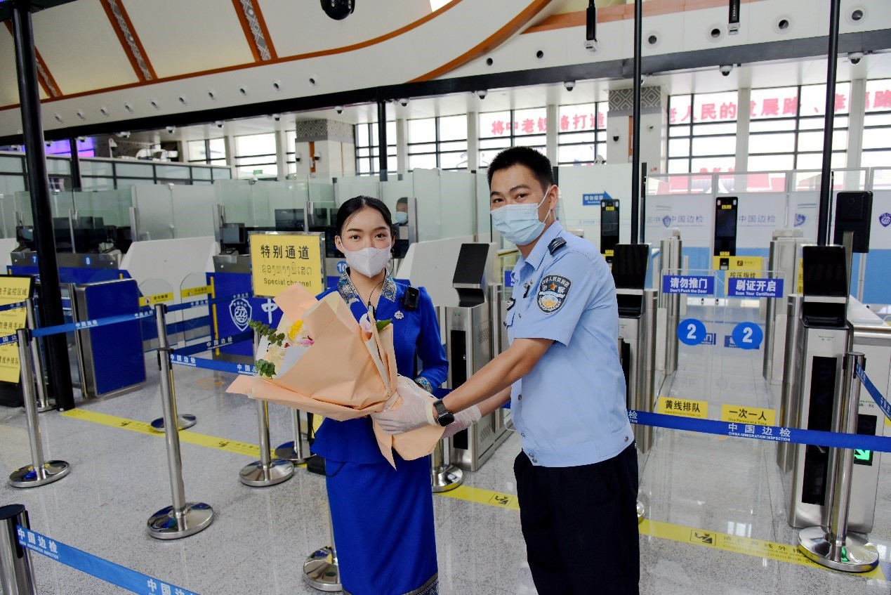磨憨出入境邊防檢查站民警為中老鐵路第100萬名出入境旅客，D888次國際旅客列車老撾籍乘務員森達拉·妮緹婭（Sengdala Nitiya），送上鮮花。黃遠飛 攝