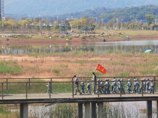 　　10月24日，秋游的幼兒園小朋友在老師帶領下走在清水塘公園里的木橋上。本報記者 常雯宜攝