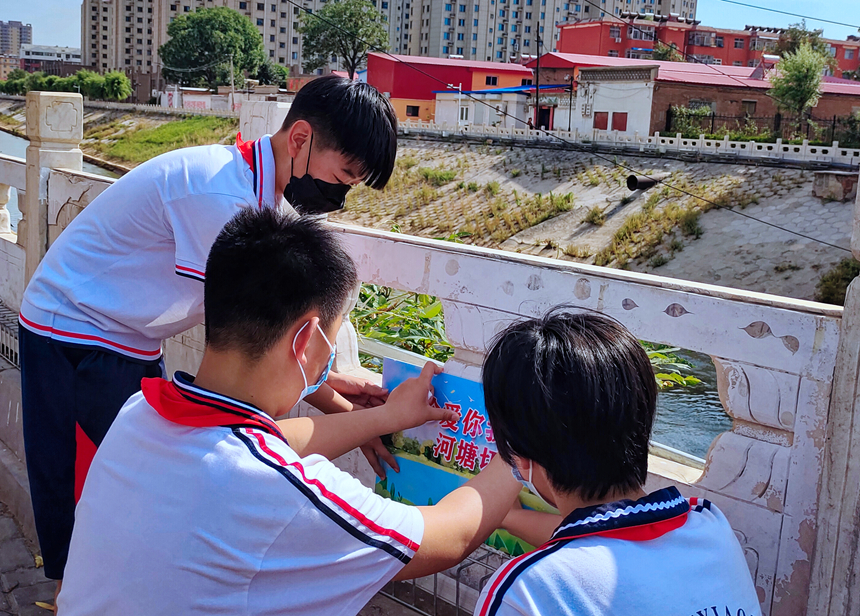 徐水小學(xué)學(xué)雷鋒志愿者在瀑河河邊張貼防溺水警示標(biāo)語。 徐水區(qū)委宣傳部供圖
