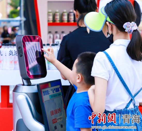 圖為一名小朋友正在和機(jī)器人“志愿者”進(jìn)行互動(dòng)。 沐聞 攝
