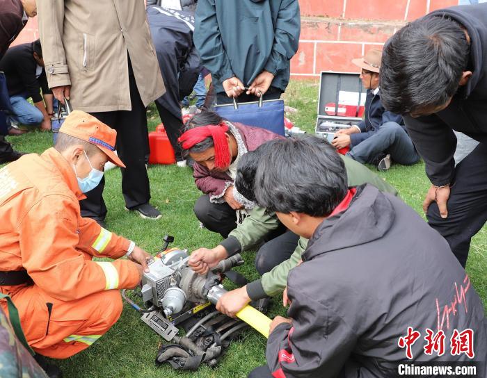 圖為森林消防員為護(hù)林員講解滅火裝備的使用方法?！〔际猩窒乐ш?供圖