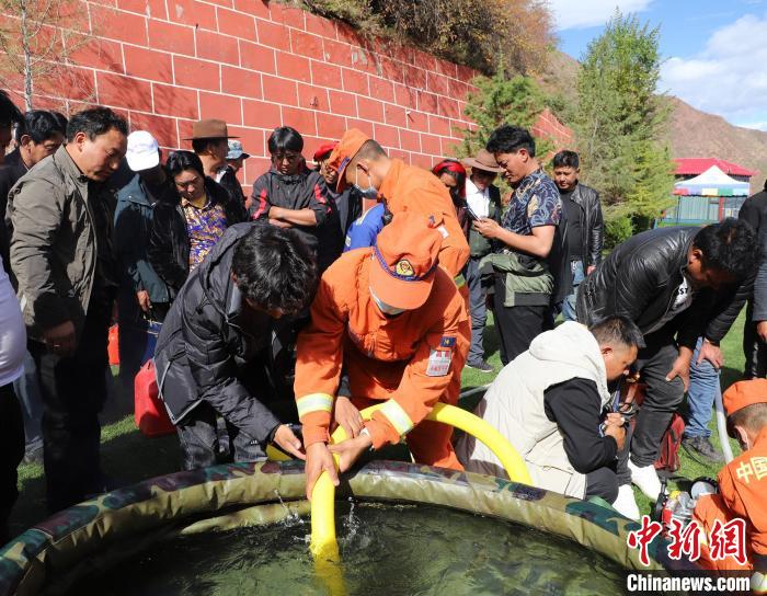 圖為森林消防員為護(hù)林員講解滅火裝備的使用方法?！〔际猩窒乐ш?供圖