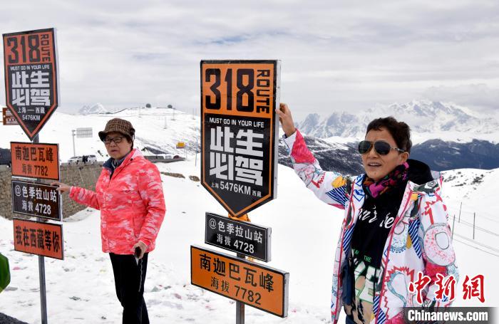 圖為5月14日，西藏林芝色季拉山觀景臺(tái)，游客與南迦巴瓦峰合影。　李林 攝