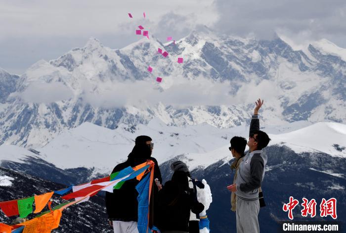圖為5月14日，游客在西藏林芝色季拉山觀景臺(tái)拋灑“隆達(dá)”(風(fēng)馬旗，藏族民眾的一種祈福方式)?！±盍?攝