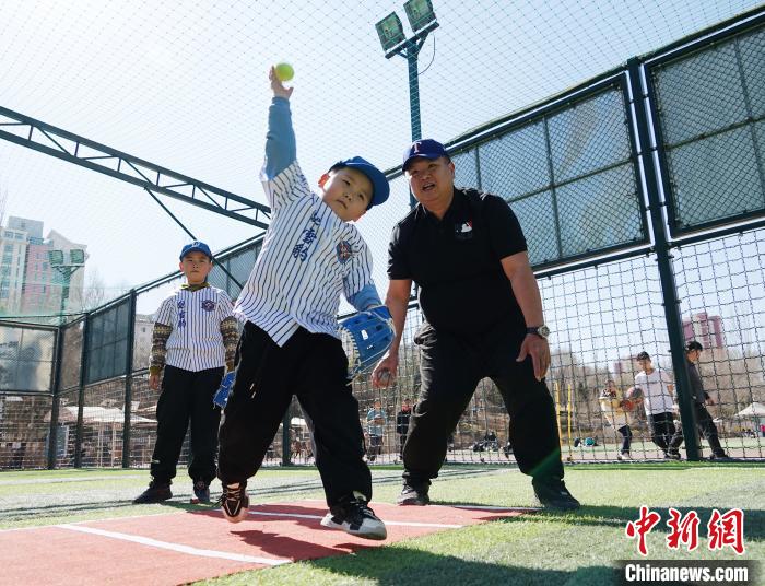 圖為來自臺灣的棒球教練劉興鴻(右)指導(dǎo)小棒球手?jǐn)S球技術(shù)?！●R銘言 攝