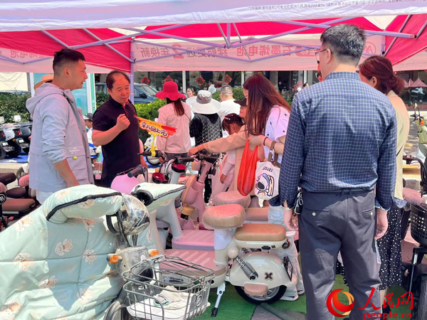 某電動自行車品牌工作人員向消費(fèi)者介紹以舊換新相關(guān)情況。人民網(wǎng)記者 杜燕飛攝