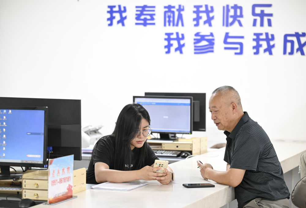 2024年6月20日，在寧夏銀川市金鳳區(qū)長城花園社區(qū)黨群服務中心，工作人員幫助居民辦理業(yè)務。圖片來源 新華社