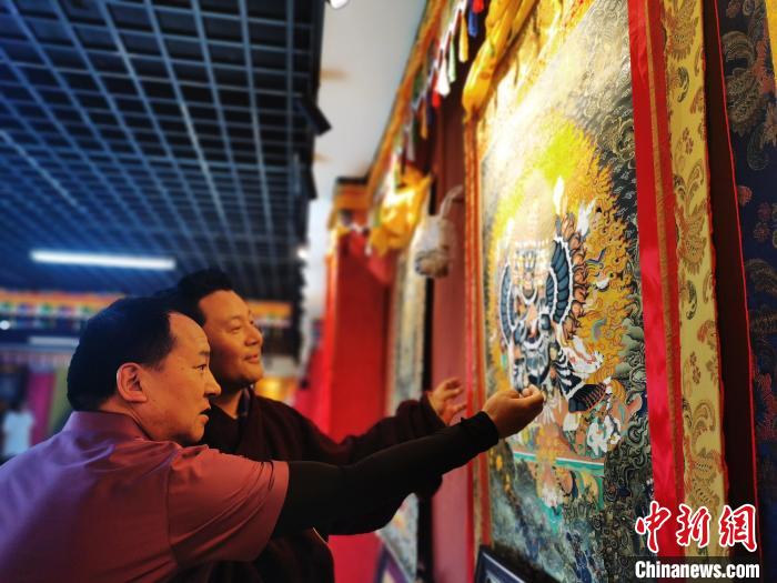 圖為久美尖措展示唐卡作品?！?zhí)砀?攝