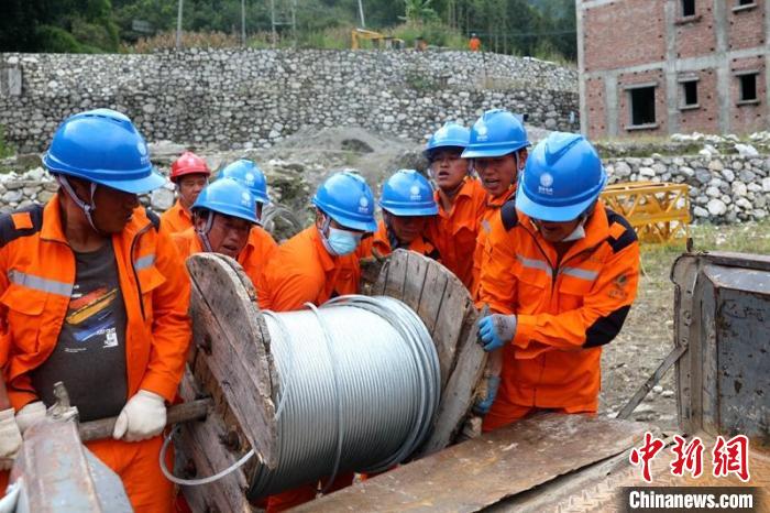 國網四川送變電公司搶險隊員將重達370公斤的鋼絞線搬上車?！⑾驸C 攝