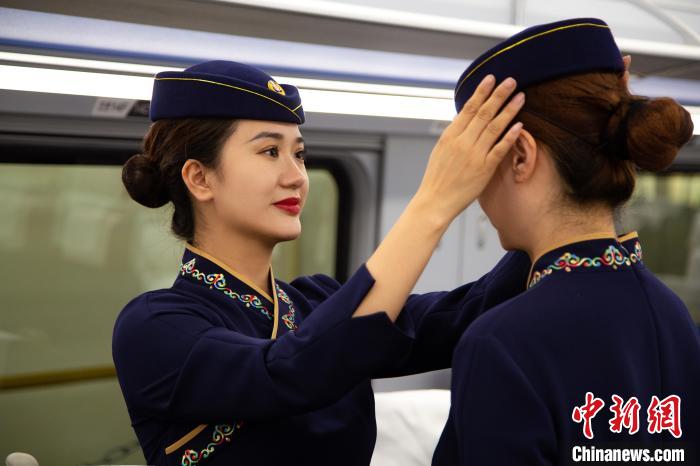 圖為青藏鐵路西格段“復興號”動車組乘務員互相整理新制服。　李磊 攝