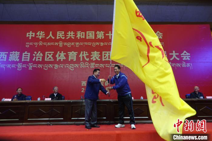 西藏自治區(qū)副主席甲熱·洛桑丹增授代表團團旗，西藏自治區(qū)體育局局長尼瑪次仁接旗?！∪轿木?攝