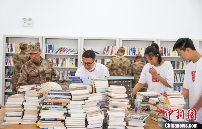圖為志愿者們和邊防戰(zhàn)士整理圖書?！詵| 攝