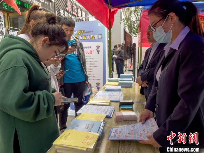 圖為工作人員正在向路過市民介紹國家反詐中心軟件的功能?！≈x牧 攝