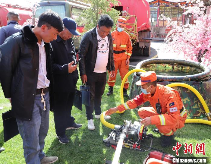 圖為森林消防員為護(hù)林員講解滅火裝備的使用方法?！〔际猩窒乐ш?duì) 供圖
