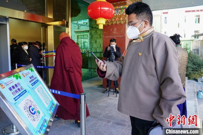 圖為政協(xié)委員掃場所碼進入會場?！〗w波 攝