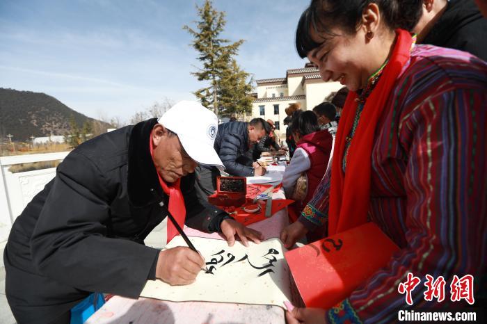 圖為林芝市文聯(lián)書法家協(xié)會(huì)會(huì)員向民眾贈(zèng)送藏文書法作品。　張力 攝