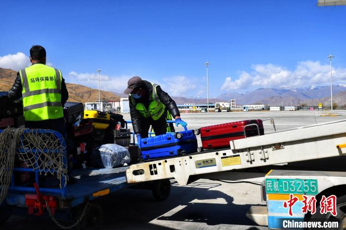 圖為機場工作人員傳送旅客行李箱?！≈芎?攝