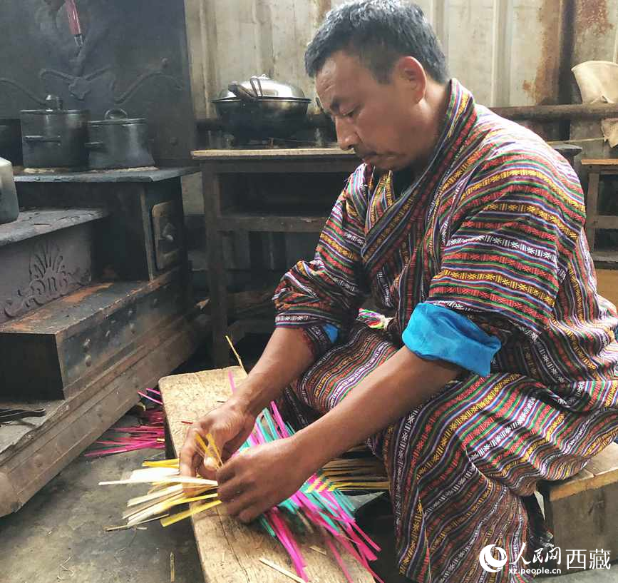 門(mén)巴族漢子愛(ài)明正在編織藤竹品。