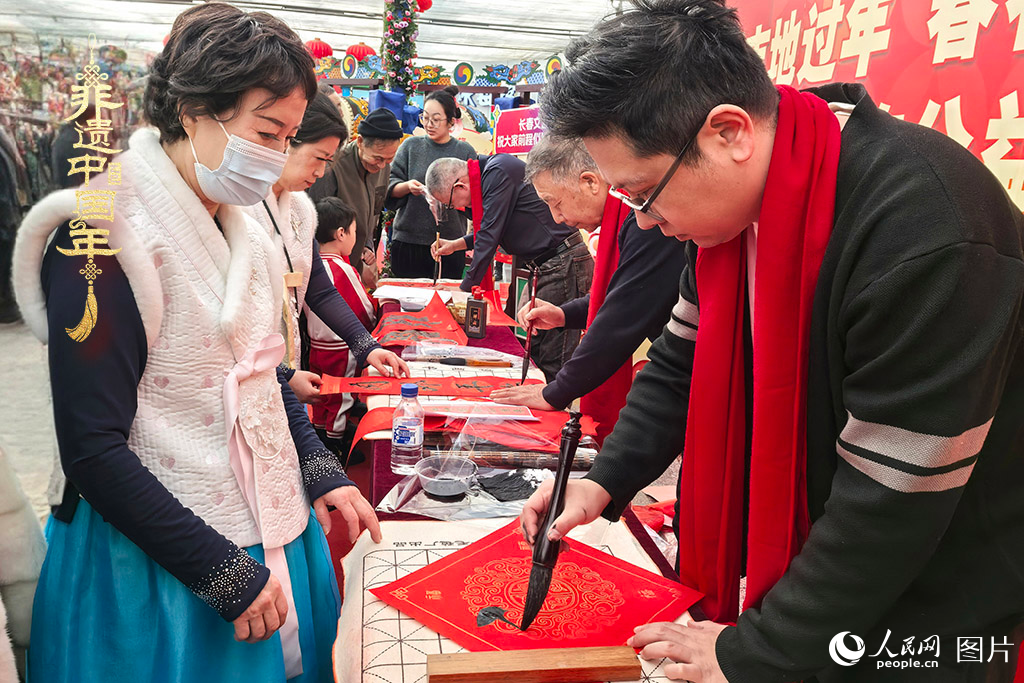 新春佳節(jié)之際，長春農(nóng)博園冬季展會(huì)火熱進(jìn)行，展廳內(nèi)，書法家現(xiàn)場書寫“?！弊郑忻裼慰图娂娚锨坝航印案！?。人民網(wǎng)記者 王海躍攝